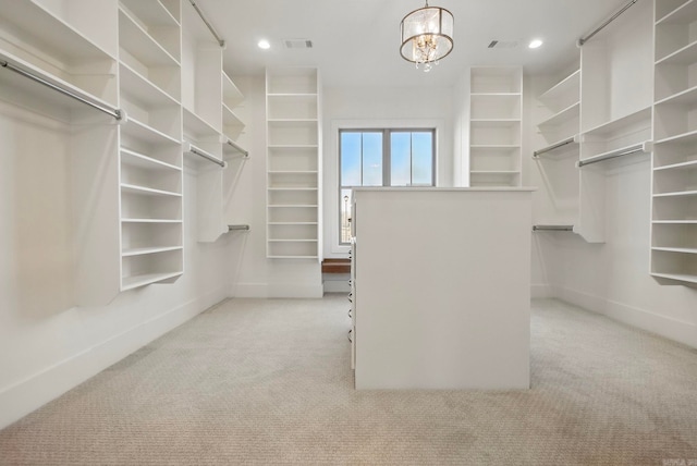 walk in closet with light carpet and an inviting chandelier