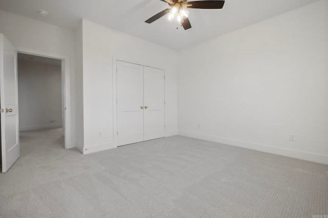 unfurnished bedroom featuring light carpet, a closet, and ceiling fan