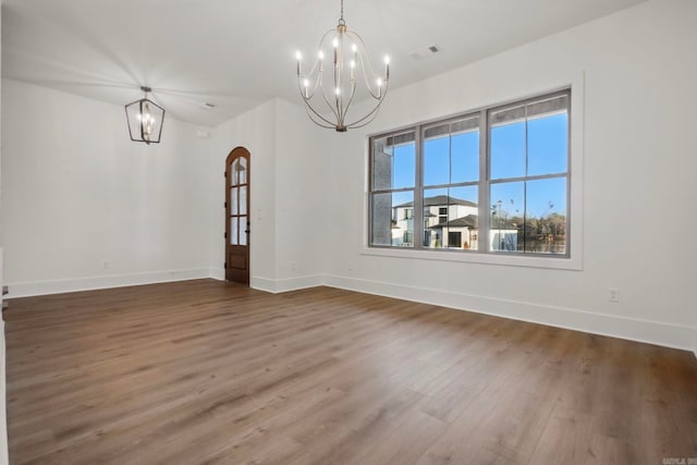 unfurnished dining area with a notable chandelier and wood-type flooring