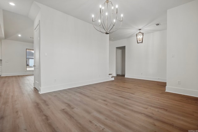 spare room with light wood-type flooring and an inviting chandelier