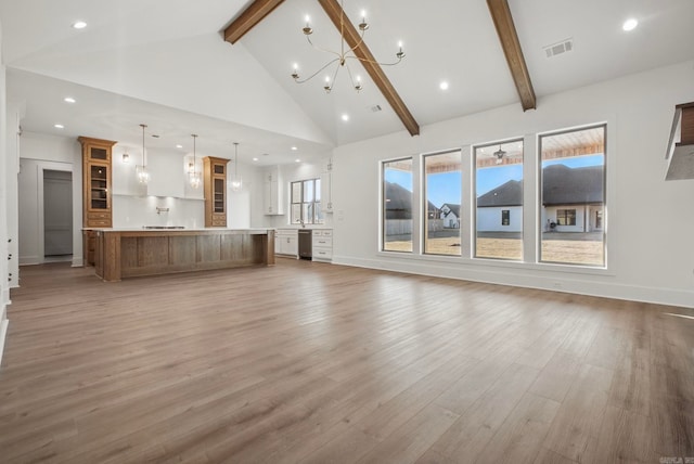 unfurnished living room featuring beamed ceiling, light hardwood / wood-style flooring, high vaulted ceiling, and an inviting chandelier