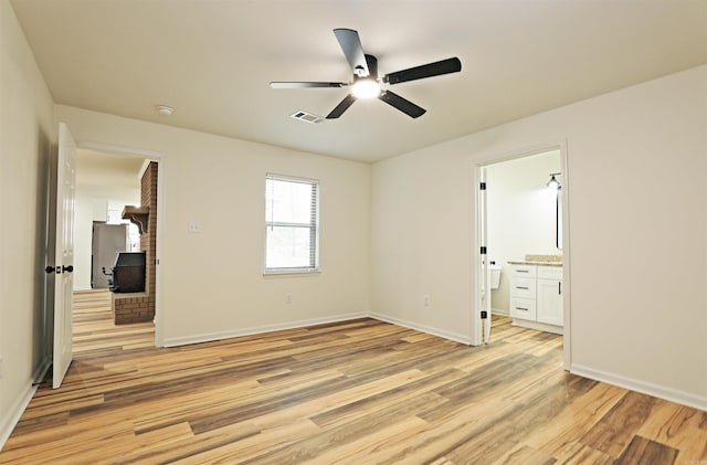 unfurnished bedroom featuring connected bathroom, light hardwood / wood-style floors, stainless steel refrigerator, and ceiling fan