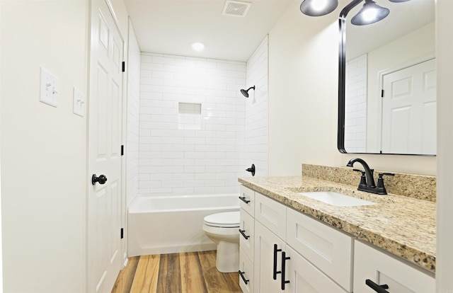 full bathroom with toilet, vanity, wood-type flooring, and tiled shower / bath