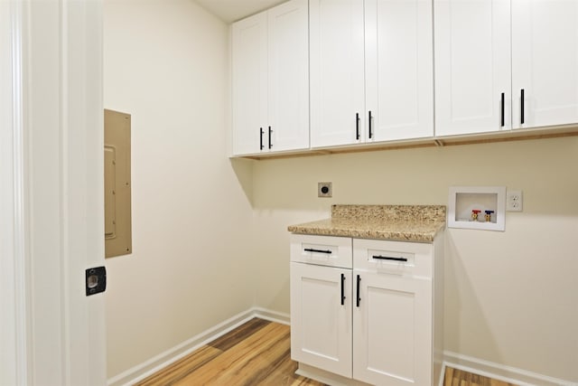 laundry room with cabinets, hookup for a washing machine, light hardwood / wood-style floors, electric dryer hookup, and electric panel