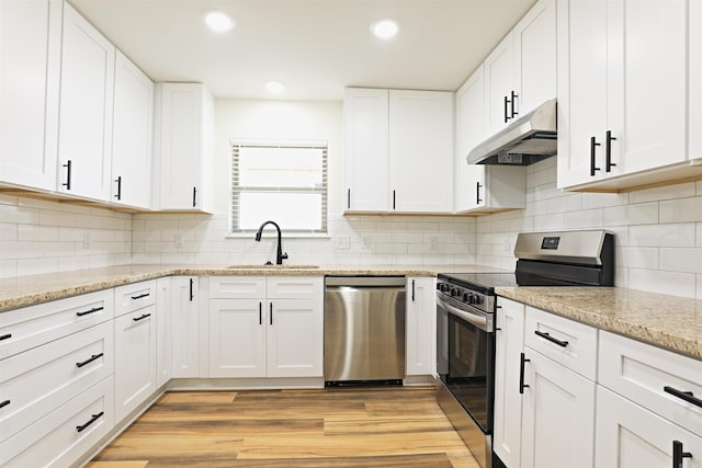 kitchen with appliances with stainless steel finishes, light hardwood / wood-style floors, white cabinetry, and sink