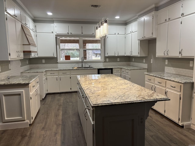 kitchen featuring a kitchen island, light stone countertops, white cabinetry, and sink