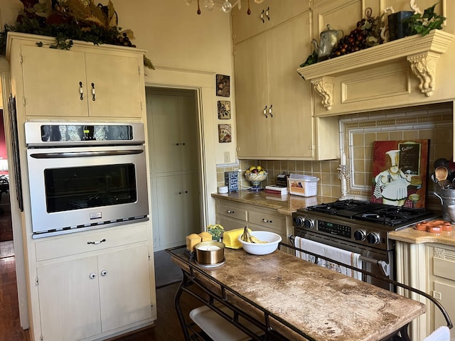 kitchen with backsplash, cream cabinetry, and appliances with stainless steel finishes