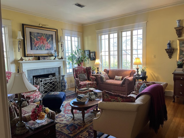 living room featuring a tile fireplace, hardwood / wood-style floors, and crown molding