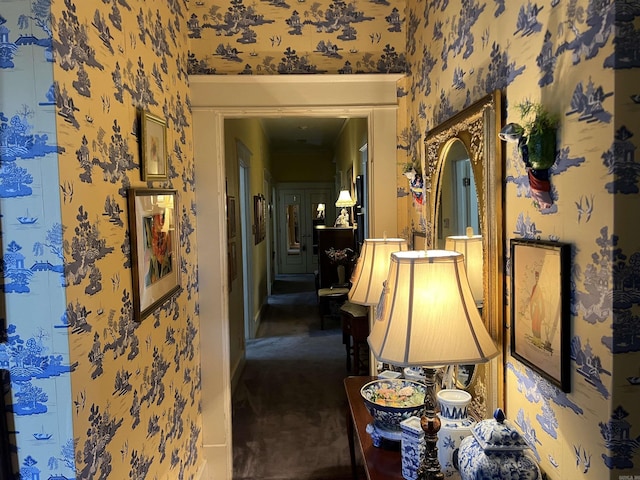 corridor with ornamental molding and dark colored carpet