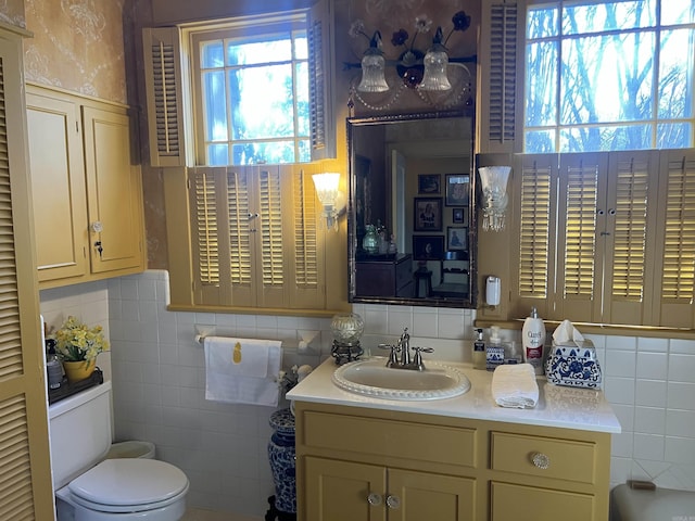 bathroom with vanity, tile walls, and toilet