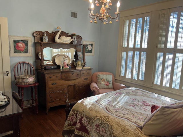 bedroom featuring multiple windows, dark wood-type flooring, and an inviting chandelier