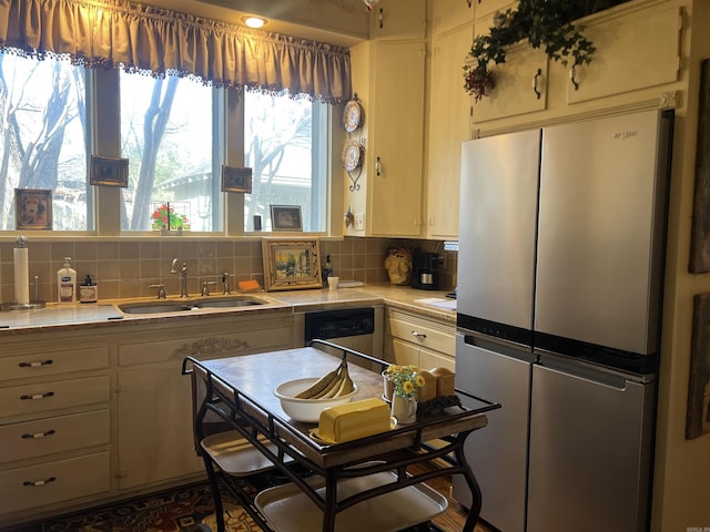 kitchen with stainless steel refrigerator, tile counters, sink, a healthy amount of sunlight, and decorative backsplash