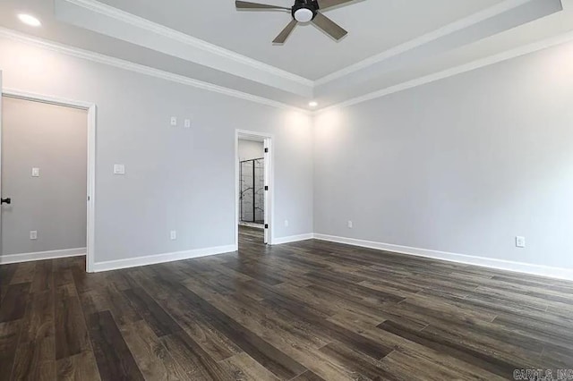 spare room with a tray ceiling, ceiling fan, crown molding, and dark hardwood / wood-style floors