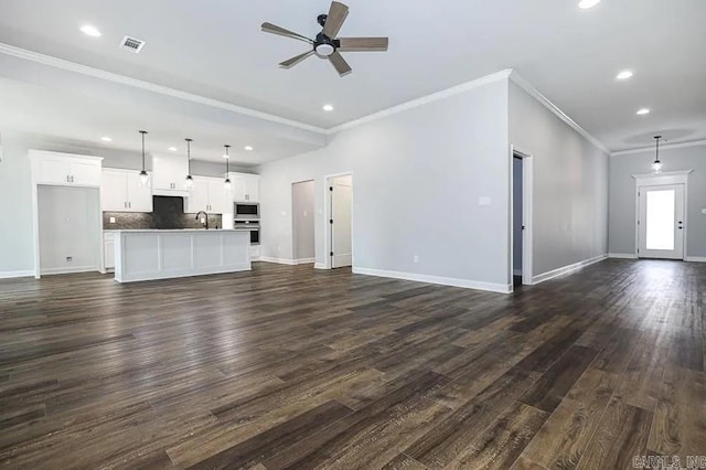 unfurnished living room featuring ceiling fan, dark hardwood / wood-style flooring, ornamental molding, and sink