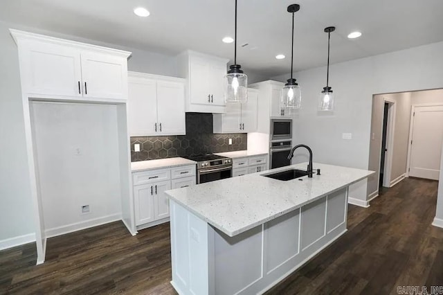 kitchen featuring white cabinets, sink, an island with sink, decorative light fixtures, and stainless steel appliances