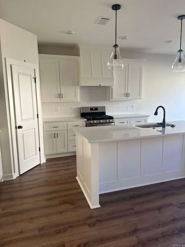 kitchen featuring stainless steel range with gas stovetop, white cabinetry, visible vents, and a sink