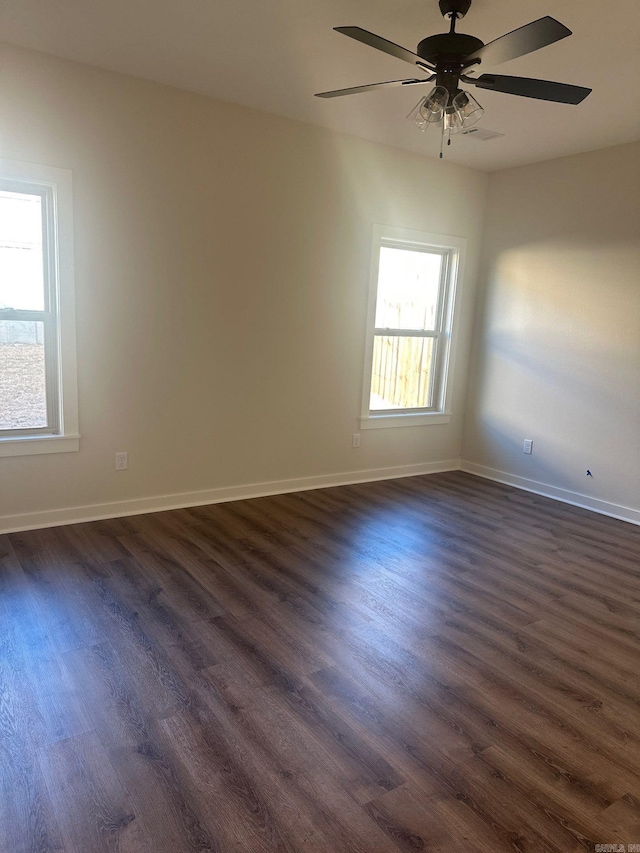 spare room with baseboards, a ceiling fan, and dark wood-type flooring