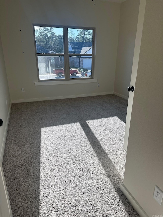 carpeted empty room featuring baseboards