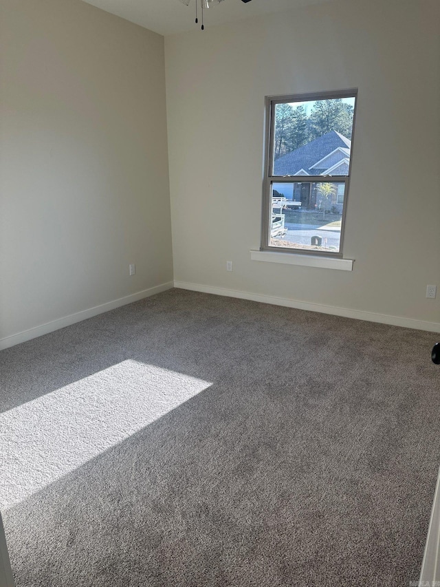 spare room with baseboards, ceiling fan, and carpet