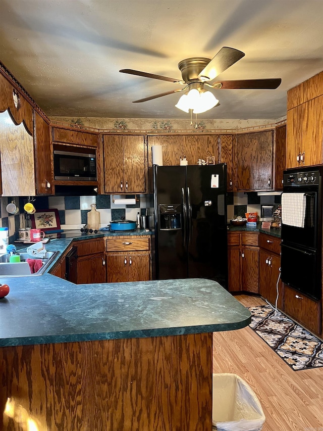 kitchen with black appliances, sink, light hardwood / wood-style flooring, ceiling fan, and kitchen peninsula