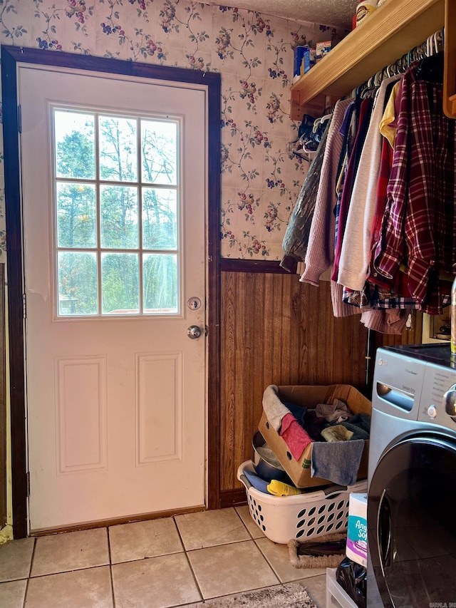 clothes washing area featuring wooden walls, light tile patterned floors, and washer / clothes dryer