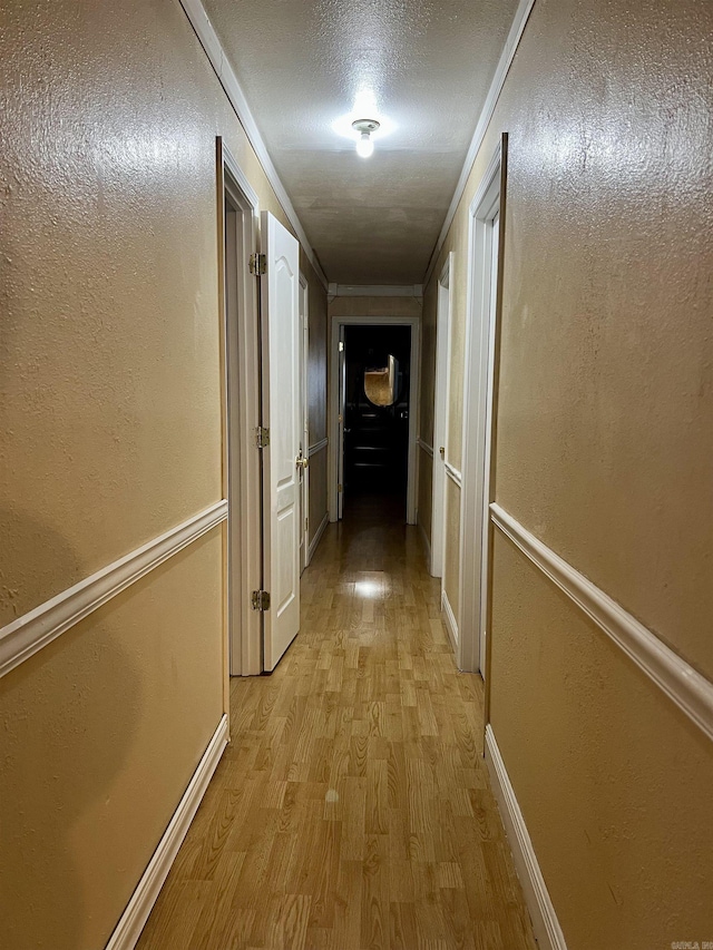 hall featuring ornamental molding, a textured ceiling, and light hardwood / wood-style flooring