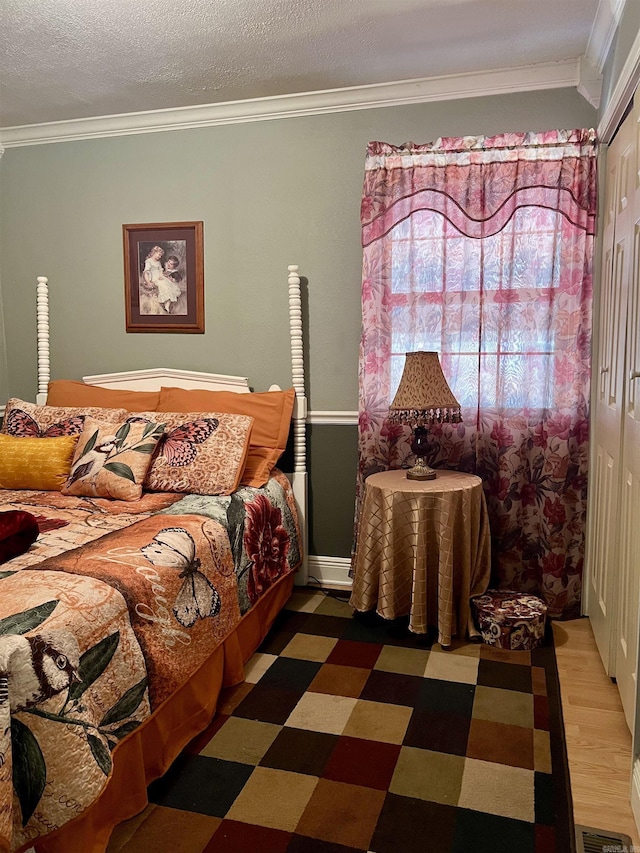 bedroom with a textured ceiling, crown molding, and a closet