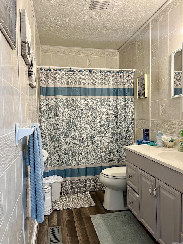 bathroom featuring a textured ceiling, vanity, tile walls, and hardwood / wood-style flooring