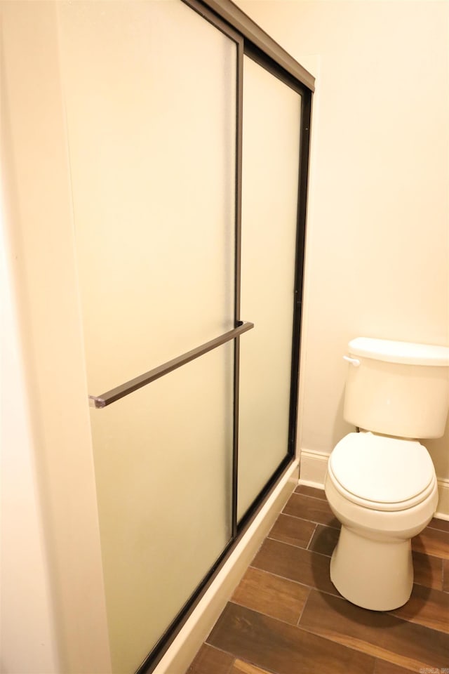 bathroom featuring toilet and a shower with shower door