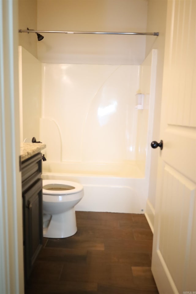 full bathroom with hardwood / wood-style flooring, vanity, toilet, and washtub / shower combination