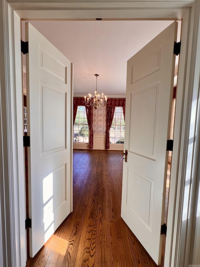 hallway featuring hardwood / wood-style flooring and a notable chandelier