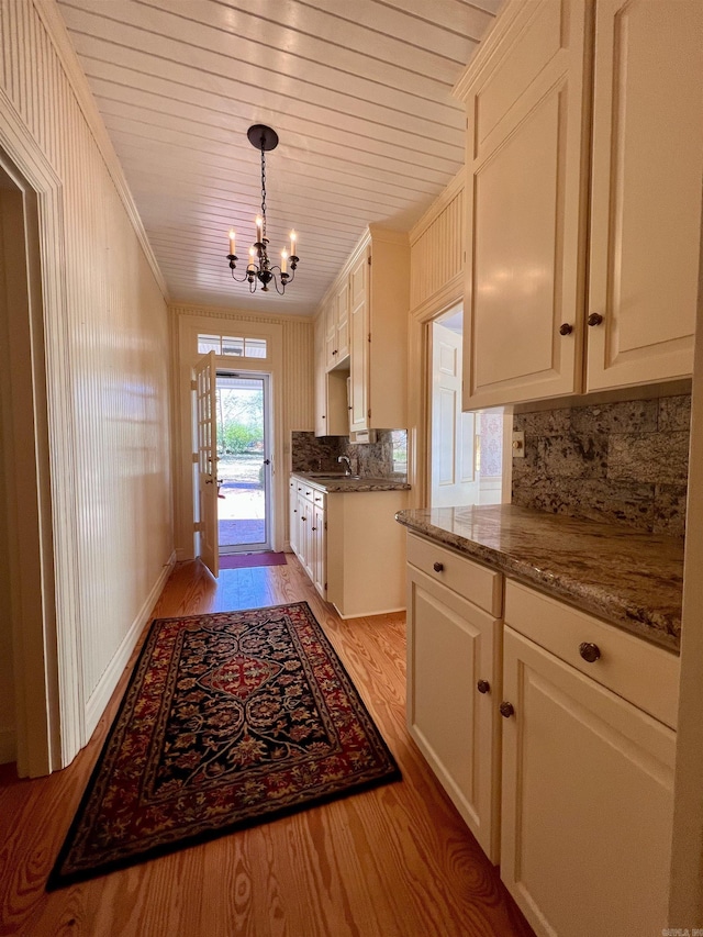 interior space with an inviting chandelier, sink, crown molding, and light hardwood / wood-style flooring