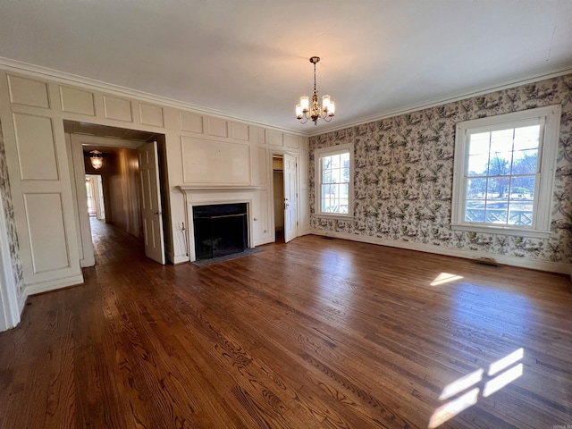 unfurnished living room with dark wood-type flooring, a notable chandelier, and ornamental molding