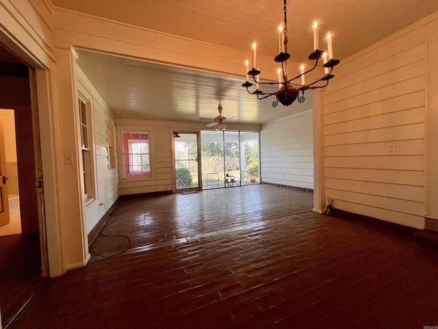 unfurnished dining area featuring wood walls and ceiling fan with notable chandelier