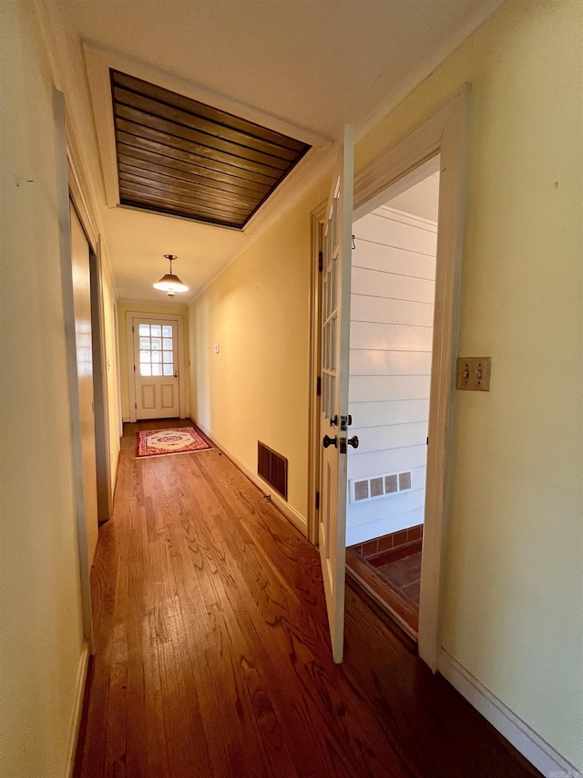 corridor with hardwood / wood-style flooring and ornamental molding