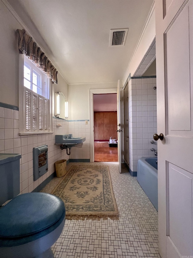 bathroom featuring a bathtub, ornamental molding, tile walls, and heating unit