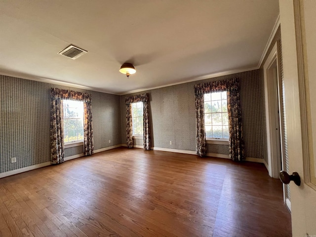 spare room featuring hardwood / wood-style floors, a wealth of natural light, and crown molding