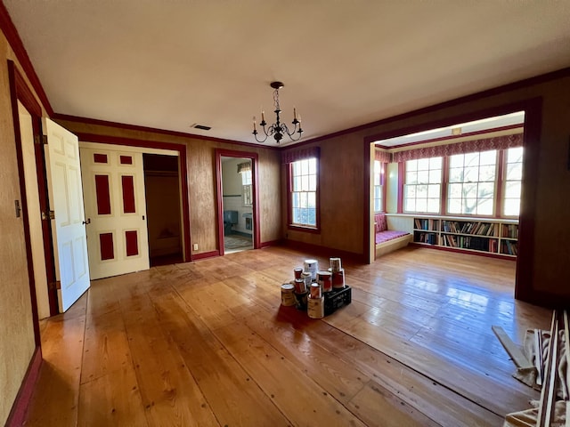 interior space featuring a wealth of natural light, crown molding, hardwood / wood-style floors, and a notable chandelier