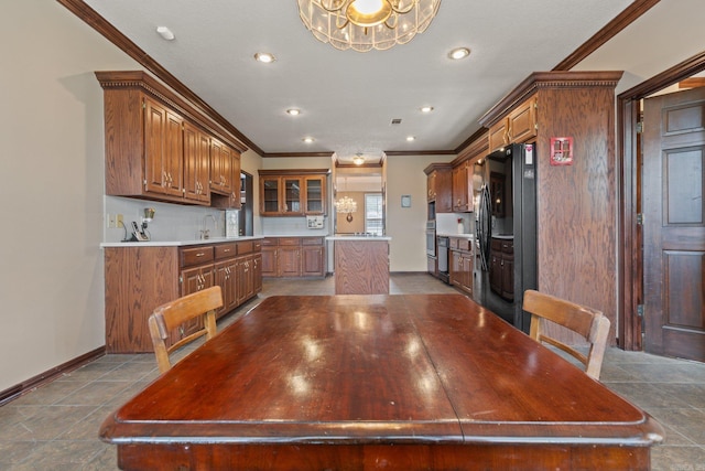 unfurnished dining area featuring an inviting chandelier, crown molding, and sink