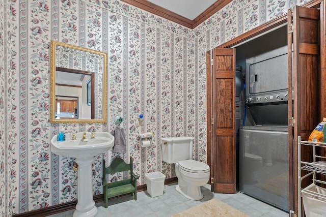 bathroom featuring toilet, ornamental molding, and stacked washer and clothes dryer