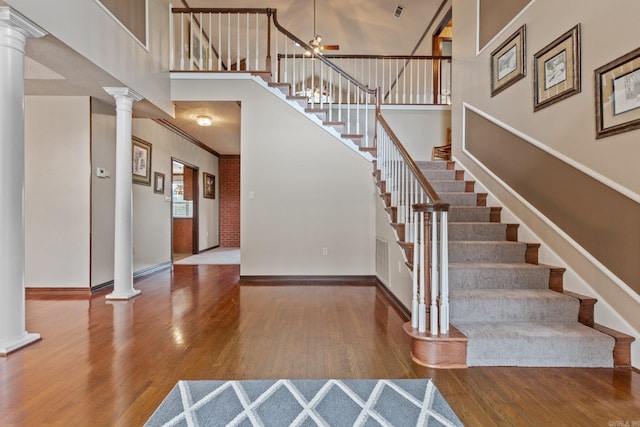 stairway featuring hardwood / wood-style flooring, ceiling fan, and decorative columns