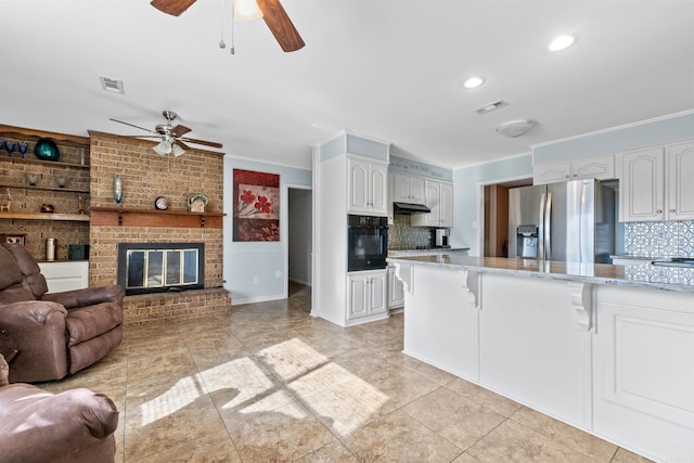 kitchen featuring white cabinets, stainless steel refrigerator with ice dispenser, tasteful backsplash, and oven