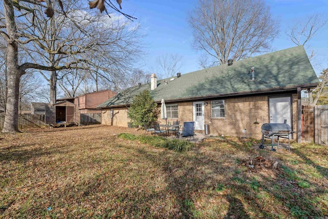 back of property featuring a patio area, a yard, and a shed