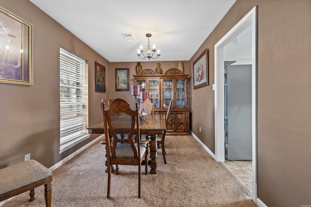 carpeted dining room with an inviting chandelier