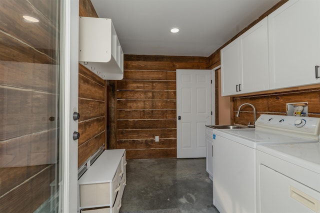 laundry room featuring cabinets, washer and dryer, wooden walls, and sink