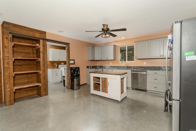 kitchen with washer and clothes dryer, sink, ceiling fan, appliances with stainless steel finishes, and a kitchen island