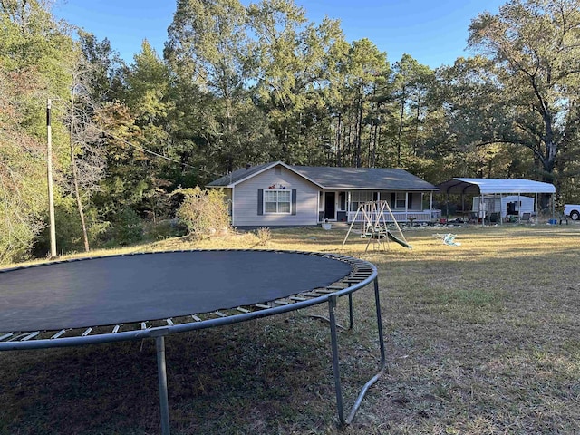 view of front facade with a front yard, a trampoline, a carport, and a playground