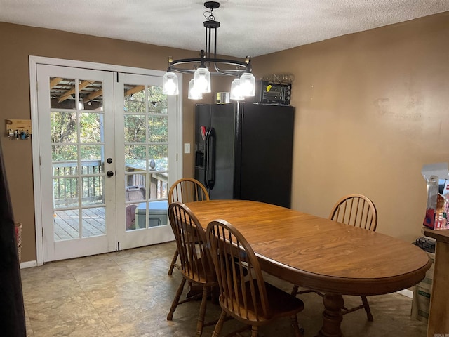 dining room featuring french doors, a textured ceiling, and an inviting chandelier