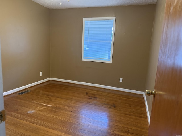 empty room with wood-type flooring and a textured ceiling