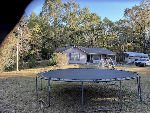 view of front of home with a front lawn, a carport, a porch, and a trampoline